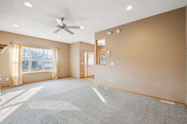 carpeted spare room featuring plenty of natural light, ceiling fan, and a textured ceiling