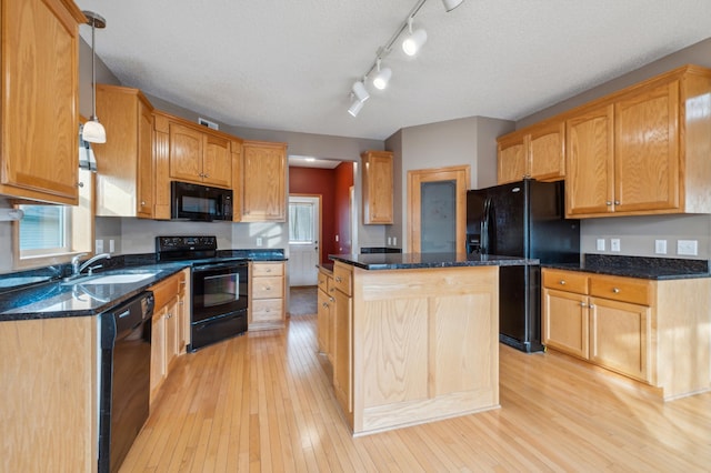 kitchen with pendant lighting, a center island, black appliances, sink, and a textured ceiling