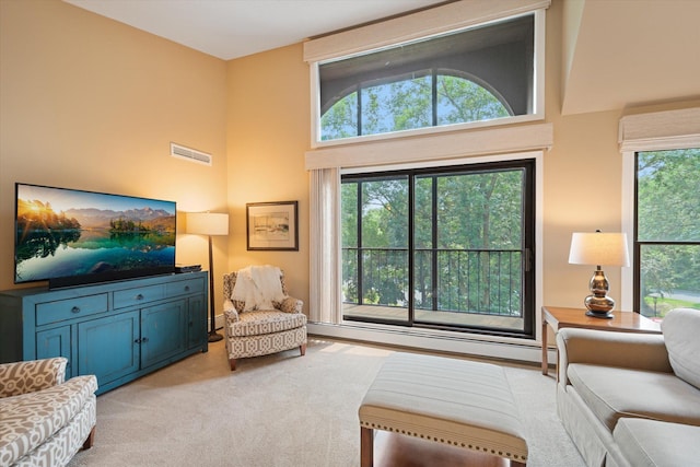 carpeted living room featuring a high ceiling and a baseboard heating unit