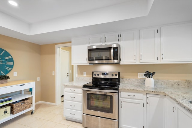 kitchen with light stone countertops, white cabinets, light tile patterned flooring, and appliances with stainless steel finishes