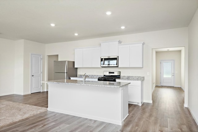 kitchen featuring light wood-type flooring, stainless steel appliances, sink, white cabinetry, and an island with sink