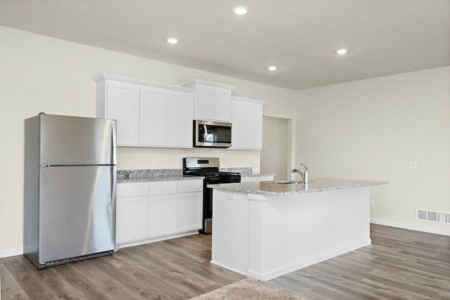 kitchen with white cabinets, light wood-type flooring, stainless steel appliances, and a center island with sink