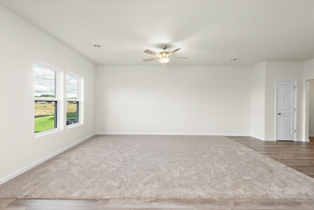 unfurnished room with dark colored carpet and ceiling fan