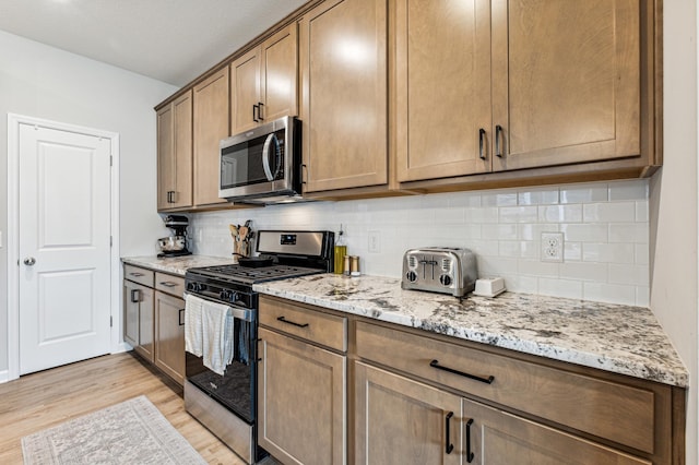 14592 Twin Lakes Cir, Burnsville, MN 55306 - kitchen featuring decorative backsplash, light stone counters, stainless steel appliances, and light wood-type flooring