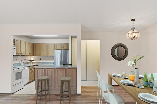 kitchen featuring sink, an inviting chandelier, light hardwood / wood-style floors, decorative light fixtures, and white appliances