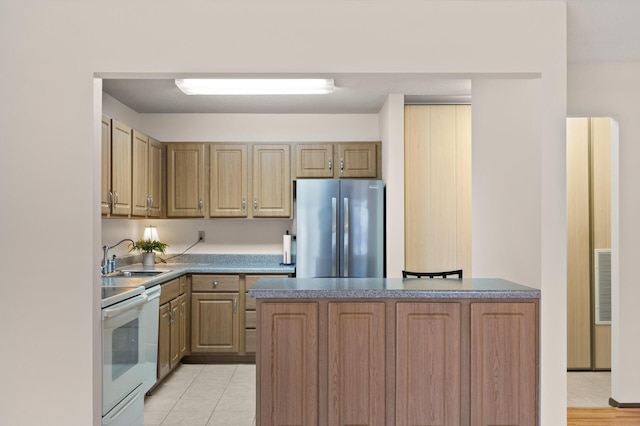 kitchen featuring light tile patterned flooring, stainless steel fridge, stove, and sink