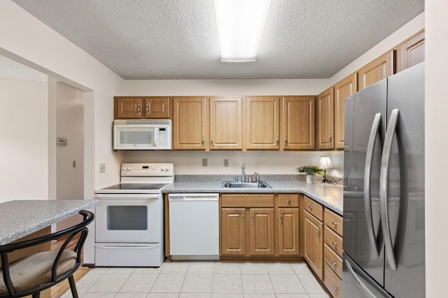 kitchen with a textured ceiling, sink, light tile patterned flooring, and white appliances