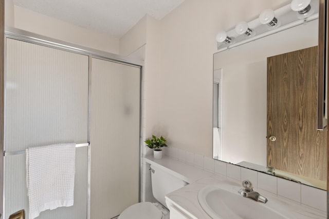 bathroom with vanity, toilet, an enclosed shower, and a textured ceiling