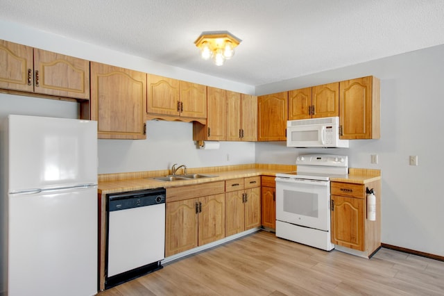 kitchen with white appliances, light wood-type flooring, a textured ceiling, and sink