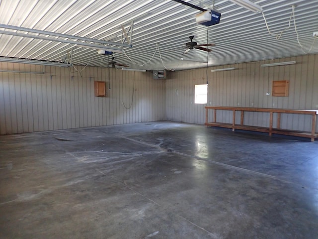 garage featuring ceiling fan, wooden walls, and a garage door opener