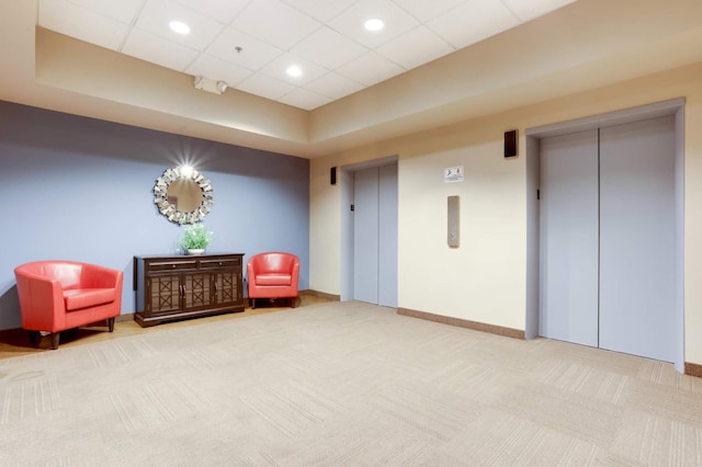 living area featuring carpet floors, elevator, and a paneled ceiling