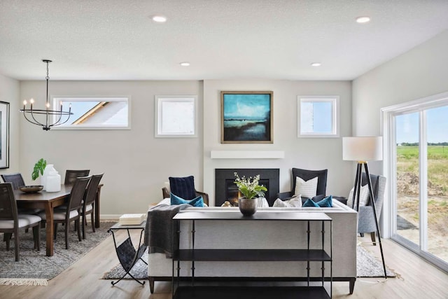 living room with light wood-type flooring, a textured ceiling, and an inviting chandelier