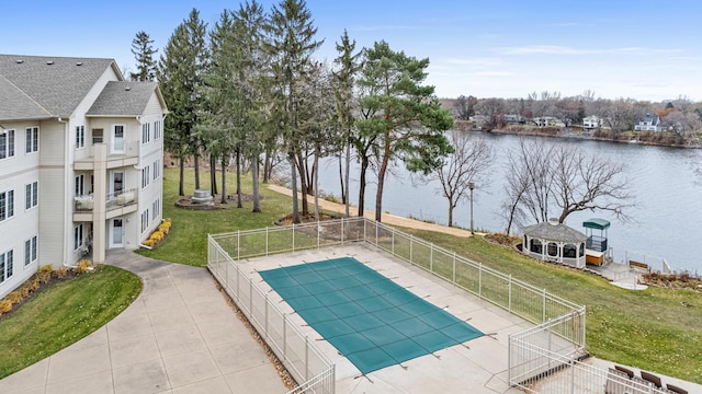 view of swimming pool featuring a patio, a water view, a yard, and an outdoor structure