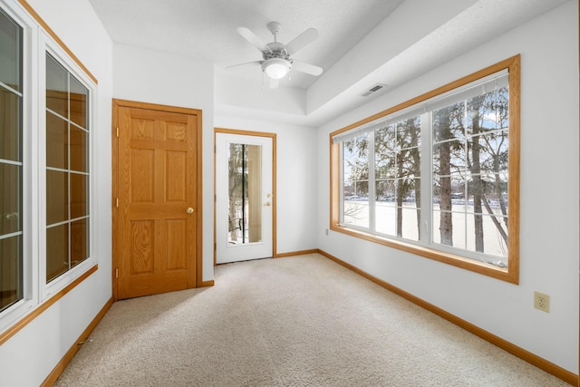 unfurnished room with light carpet, a tray ceiling, and ceiling fan