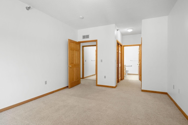 unfurnished bedroom featuring ensuite bathroom and light carpet