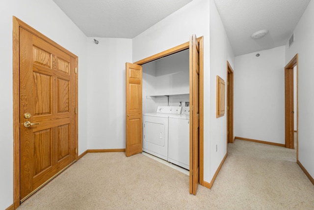 laundry room featuring washing machine and dryer, light carpet, and a textured ceiling