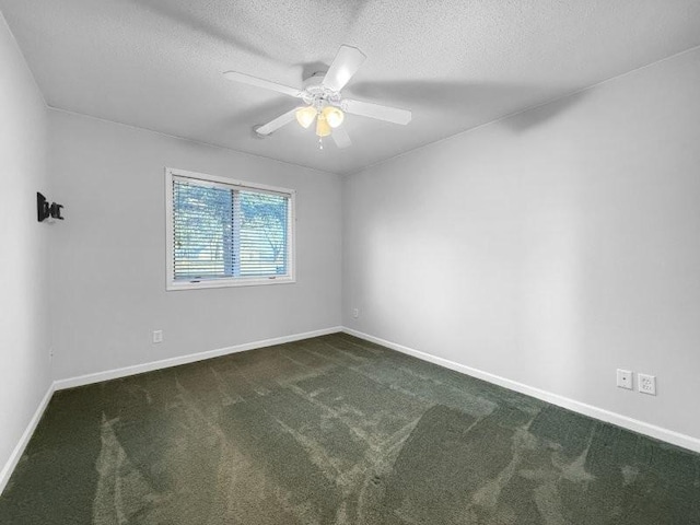 empty room featuring ceiling fan, dark carpet, and a textured ceiling