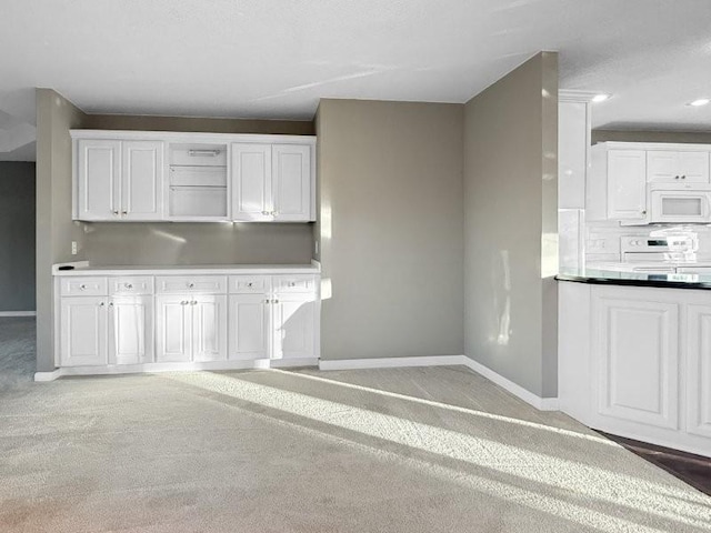 kitchen featuring white appliances, carpet floors, and white cabinetry