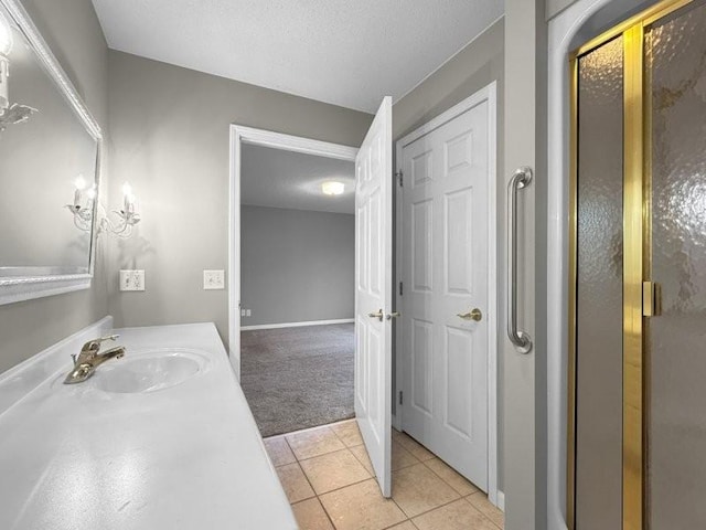 bathroom with tile patterned flooring, vanity, a textured ceiling, and walk in shower