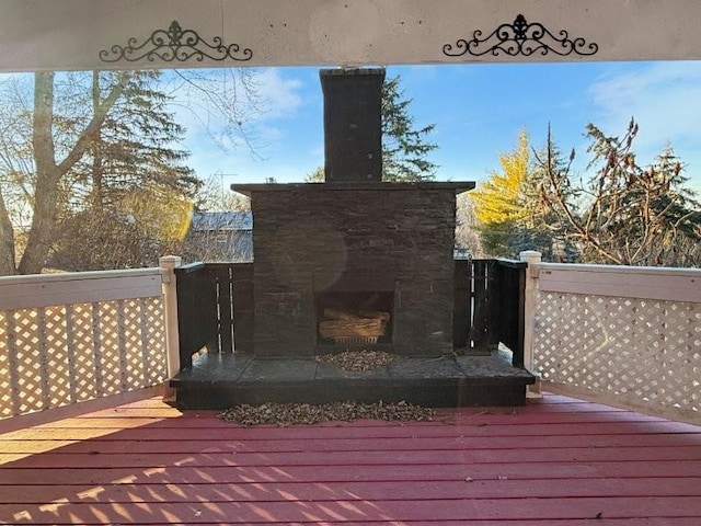 wooden terrace with an outdoor stone fireplace