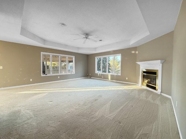 unfurnished living room featuring a textured ceiling, a tray ceiling, and ceiling fan