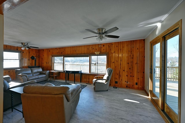 living room featuring crown molding, ceiling fan, and wooden walls