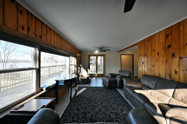 living room with a water view, crown molding, wooden walls, hardwood / wood-style flooring, and ceiling fan