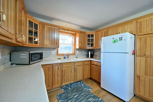 kitchen with decorative light fixtures, white refrigerator, decorative backsplash, and sink