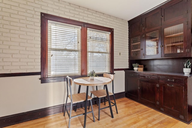 dining room with brick wall and light wood-type flooring