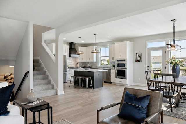 living room featuring a healthy amount of sunlight, sink, and light hardwood / wood-style floors