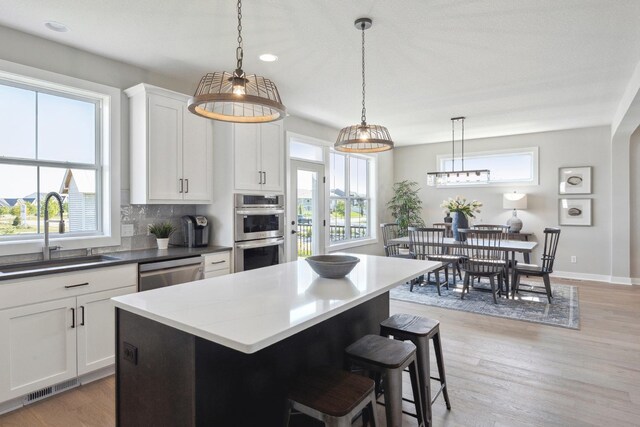 kitchen with white cabinets, appliances with stainless steel finishes, tasteful backsplash, and sink