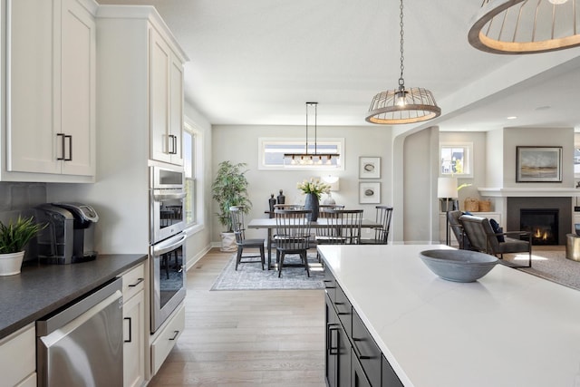 kitchen with plenty of natural light, white cabinets, hanging light fixtures, and appliances with stainless steel finishes