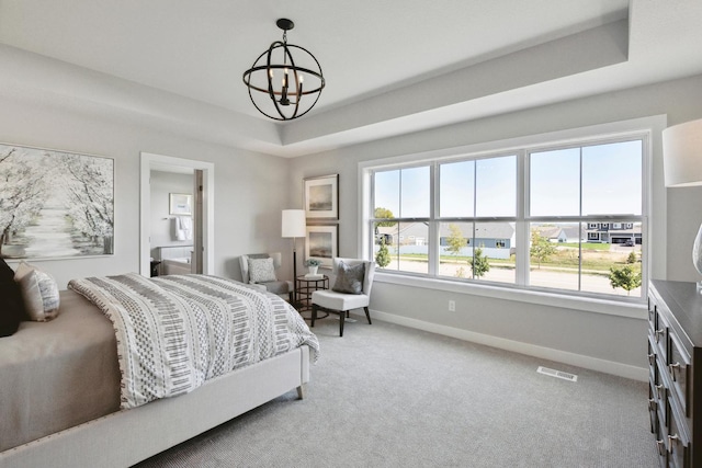 bedroom featuring a raised ceiling, carpet floors, and an inviting chandelier