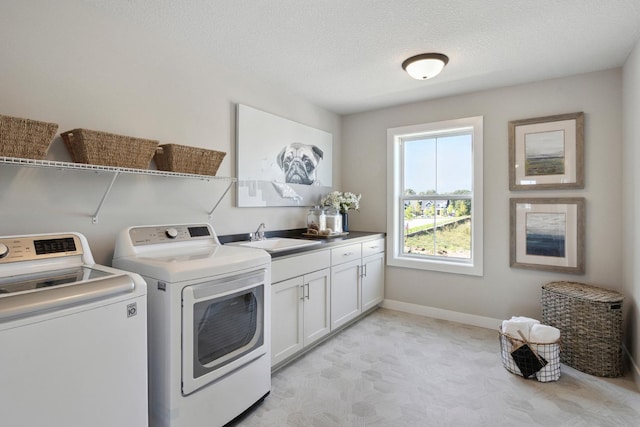 washroom with a textured ceiling, cabinets, independent washer and dryer, and sink