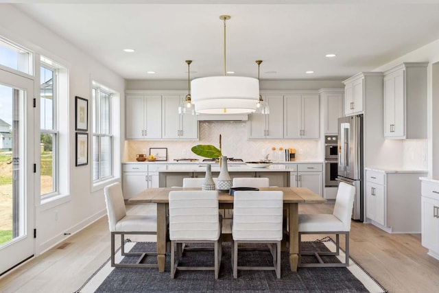 kitchen with pendant lighting, light wood-type flooring, a breakfast bar area, and appliances with stainless steel finishes