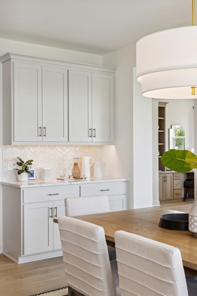 bar featuring white cabinets, light wood-type flooring, and tasteful backsplash