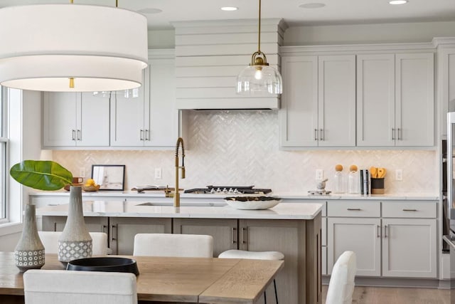 kitchen featuring backsplash, a breakfast bar, pendant lighting, and light hardwood / wood-style flooring