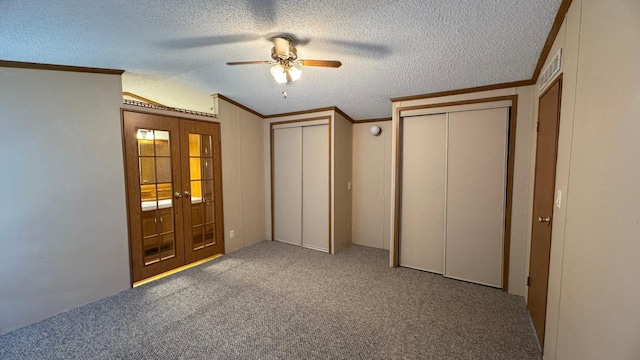 unfurnished bedroom featuring ceiling fan, carpet floors, a textured ceiling, and french doors