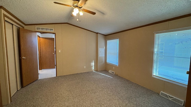 interior space with a wealth of natural light, ceiling fan, vaulted ceiling, a textured ceiling, and ornamental molding