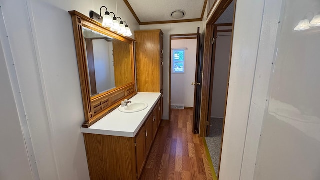 bathroom with hardwood / wood-style flooring, vanity, a textured ceiling, and ornamental molding