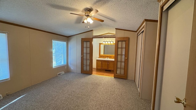 unfurnished bedroom featuring light carpet, french doors, ornamental molding, vaulted ceiling, and ceiling fan