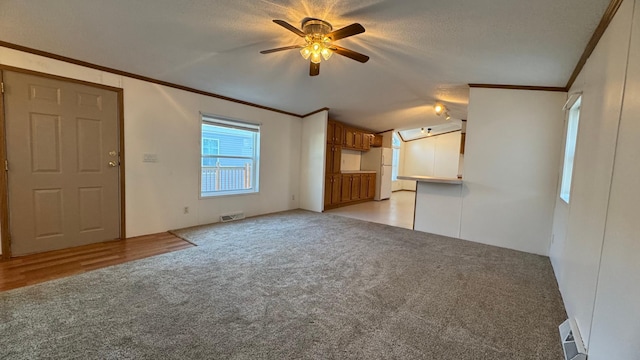 unfurnished living room featuring ceiling fan, crown molding, light carpet, and a textured ceiling