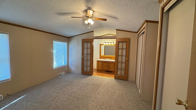 unfurnished bedroom with light carpet, french doors, ceiling fan, connected bathroom, and lofted ceiling