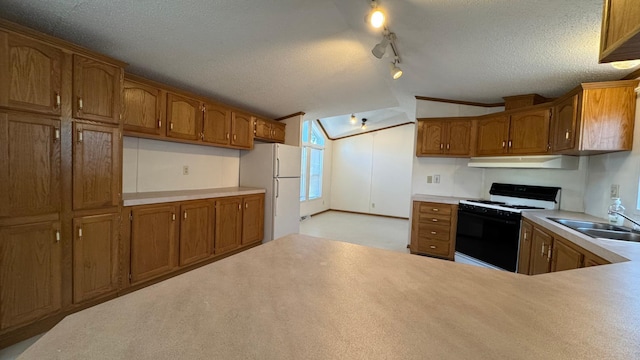 kitchen with sink, a textured ceiling, lofted ceiling, track lighting, and white appliances