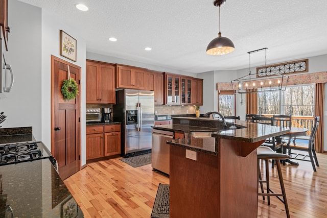 kitchen with a textured ceiling, a kitchen bar, stainless steel appliances, sink, and hanging light fixtures