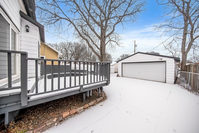 snow covered deck featuring an outbuilding and a garage