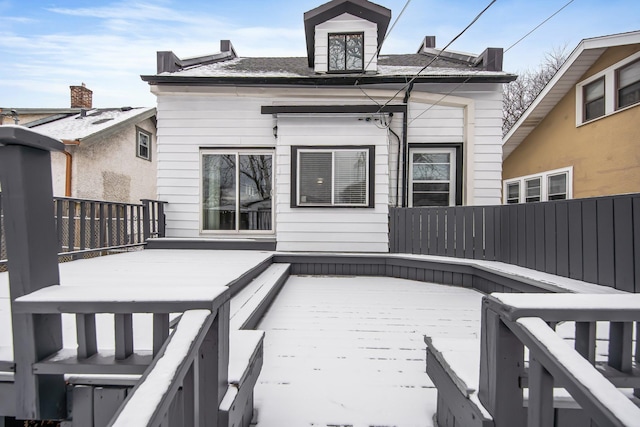 snow covered house with a wooden deck