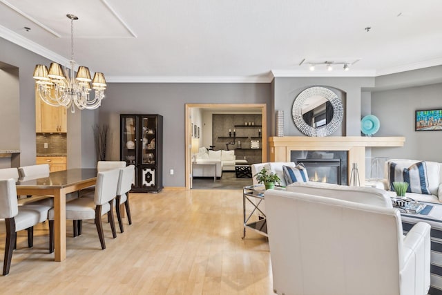 dining room with ornamental molding, an inviting chandelier, and light hardwood / wood-style flooring