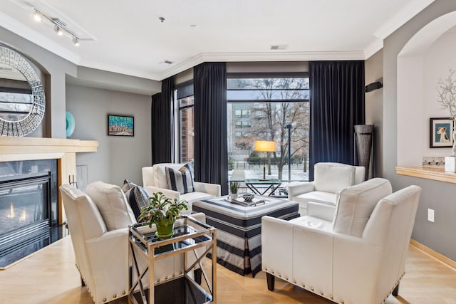 living room featuring track lighting, ornamental molding, and light hardwood / wood-style flooring