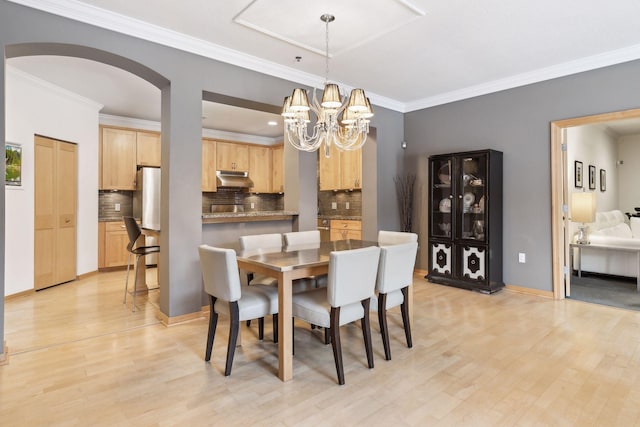 dining area with ornamental molding, a chandelier, and light hardwood / wood-style flooring